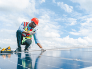 un operaio con dispositivi di sicurezza installa un impianto fotovoltaico un un tetto.