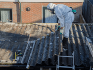 uno operaio con dispositivi di sicurezza rimuovono amianto dal tetto 