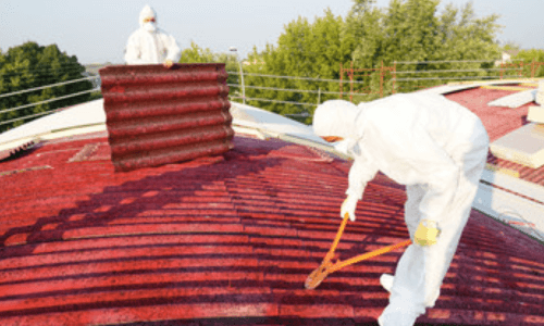 due addetti con dispositivi di sicurezza effettuano un trattamento di bonifica su un tetto ricoperto di amianto